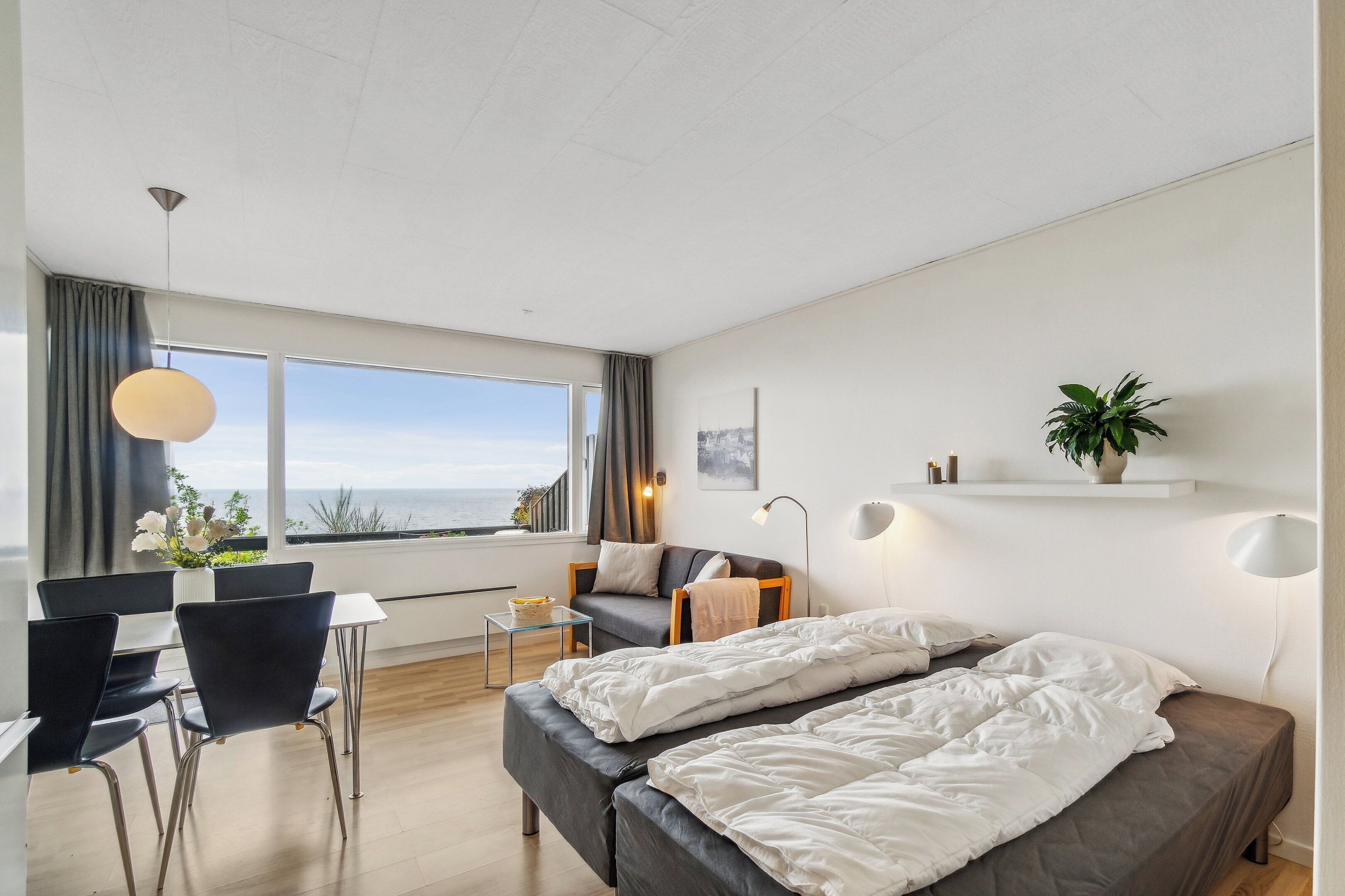 A modern hotel room with a large window, a bed, a desk, and a chair.