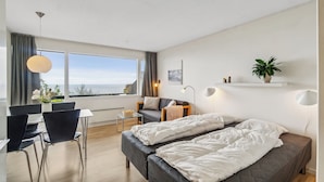 Una habitación de hotel moderna con un gran ventanal, una cama, un escritorio y una silla.
