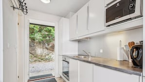 Una cocina moderna con armarios blancos, horno empotrado, microondas y fregadero.