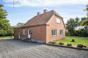 A single-story brick house with a sloped roof, a front door, and a small front yard with gravel and plants. - 750 m2 countryside idyll with activity room (Haderslev)
