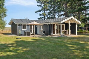 A two-story house with a covered patio, a barbecue grill, and a small outdoor seating area.