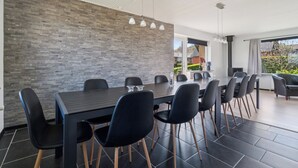 A modern dining area with a long table, black chairs, and a brick wall. - Modern holiday home with sea view in Tejn (Allinge-Sandvig)