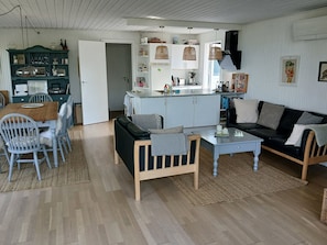 A spacious living area with a dining table, a sofa, and a kitchen in the background.
