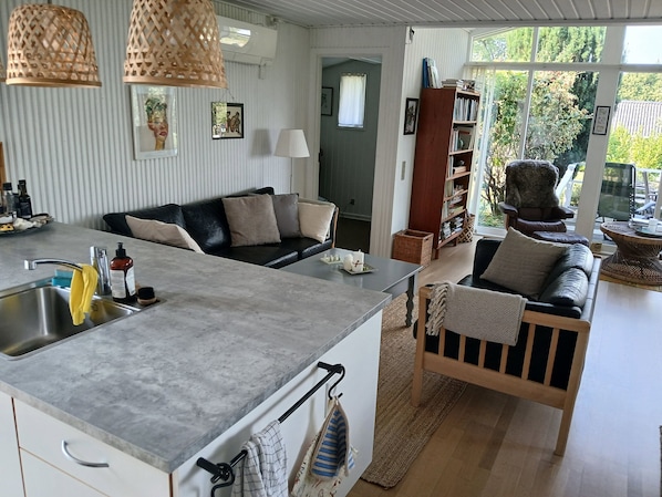Eine moderne Küche mit Kochinsel, einem Essbereich inklusive Sofa und einem Bücherregal.