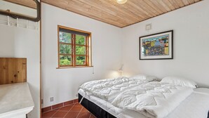 Une chambre à coucher avec un lit, une fenêtre, un tableau et un plafond en bois.