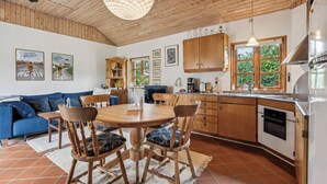 Une cuisine moderne avec des meubles en bois, une table à manger avec des chaises, un canapé bleu et un ventilateur de plafond.