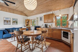Een moderne keuken met houten kasten, een eettafel met stoelen, een blauwe bank en een plafondventilator.
