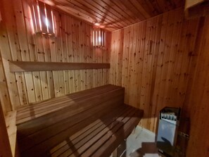 A wooden sauna with a bench and a small heater.