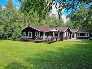 A wooden cabin with a covered porch, outdoor seating, and a barbecue area.