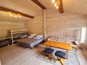 En mysig stuga med en våningssäng, soffa, träbord och träningsstolar.