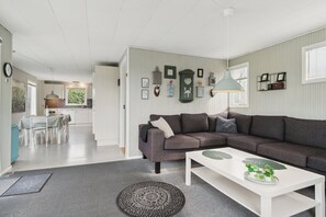 A modern living room with a grey sectional sofa, a white coffee table, and a patterned rug.