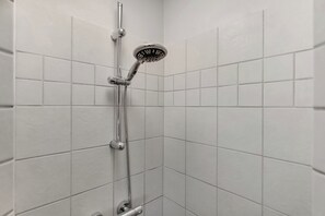 A shower with a handheld showerhead and a vertical rain showerhead, set in a corner with white tiled walls.