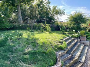 A garden with a stone staircase leading up to a wooden deck.
