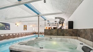 A hot tub with a view of a swimming pool, a ceiling with a blue beam, and a wall with a tile pattern. - Lovely house with pool near charming Aarhus (Hasselager)