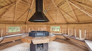 A wooden interior with a central fireplace, benches, and windows. - Lovely house with pool near charming Aarhus (Hasselager)