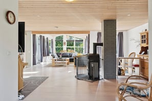 Un vaste espace de vie dotĂ© dâune cheminĂ©e, de parquets en bois et offrant une vue dĂ©gagĂ©e grĂące Ă de grandes fenĂȘtres.