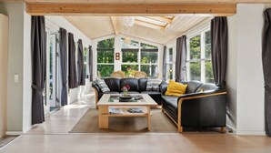 Ein modernes Wohnzimmer mit einer Couch, einem Couchtisch und großen Fenstern.