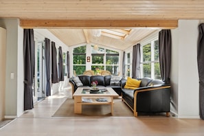 Ein modernes Wohnzimmer mit einer Couch, einem Couchtisch und großen Fenstern.