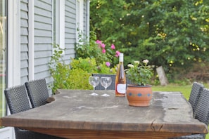A wooden table with two wine glasses, a bottle, and a potted plant.