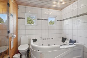 Ein Badezimmer mit Toilette, einer Badewanne und zwei Fenstern.