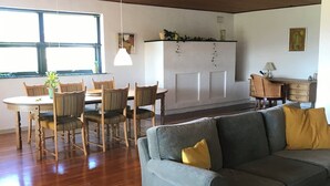 A modern living room with a grey sofa, wooden dining table, chairs, and a kitchen area with a white cabinet. - Lovely holiday home on Lolland (Errindlev)