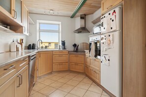 A kitchen with wooden cabinets, a stainless steel dishwasher, a double oven, and a refrigerator with magnets.
