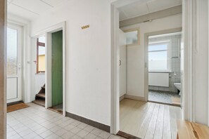 A hallway with a tiled floor, a green door, and a view into a bathroom with a toilet and sink. - Idyllic country house with sea view and sunsets (Rønne)