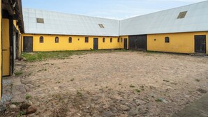 Ein Innenhof mit gelben Gebäuden, einem Kopfsteinpflasterboden und einem Metalldach.