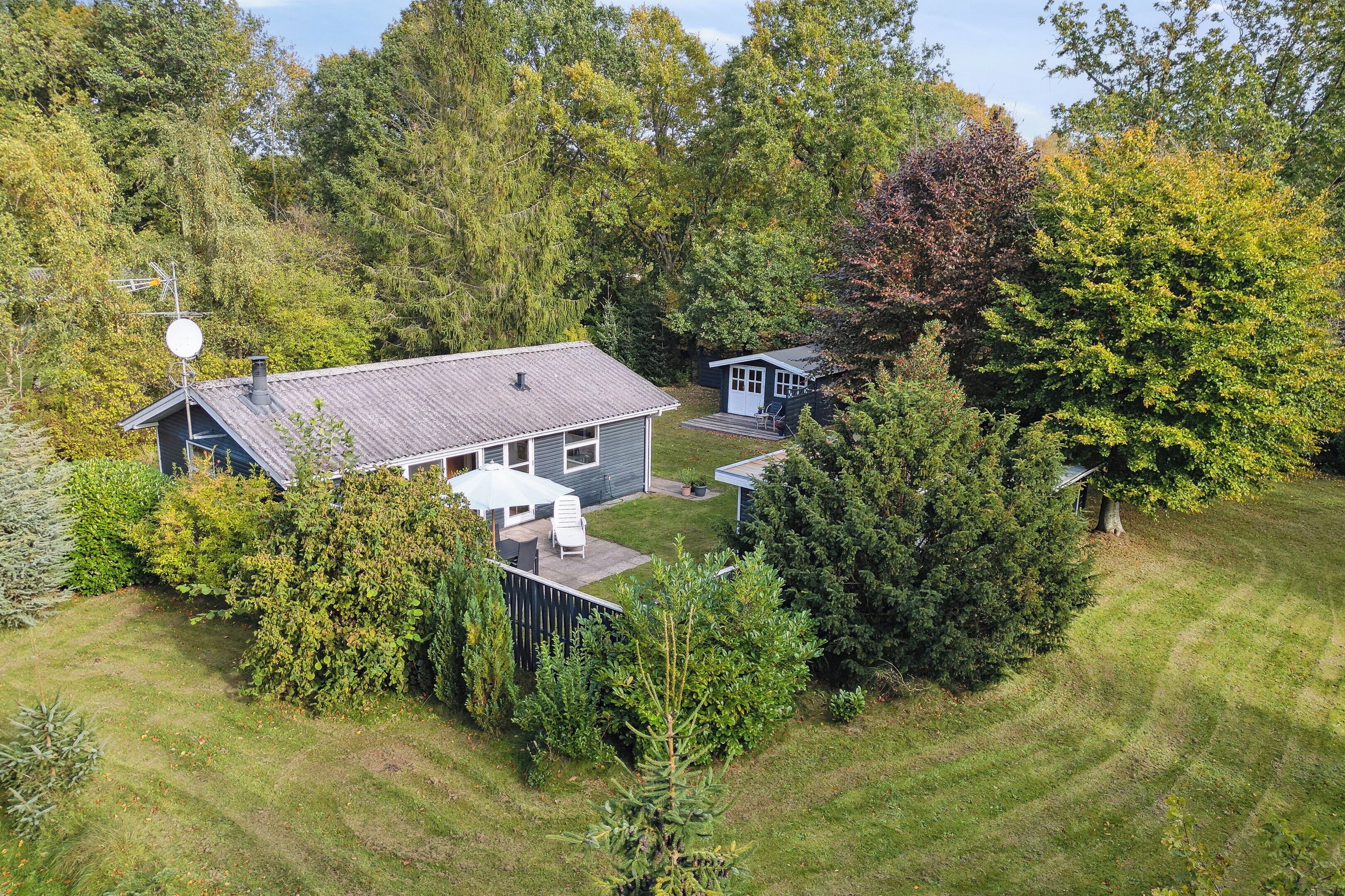 A house with a fenced yard, a satellite dish, and a small shed.