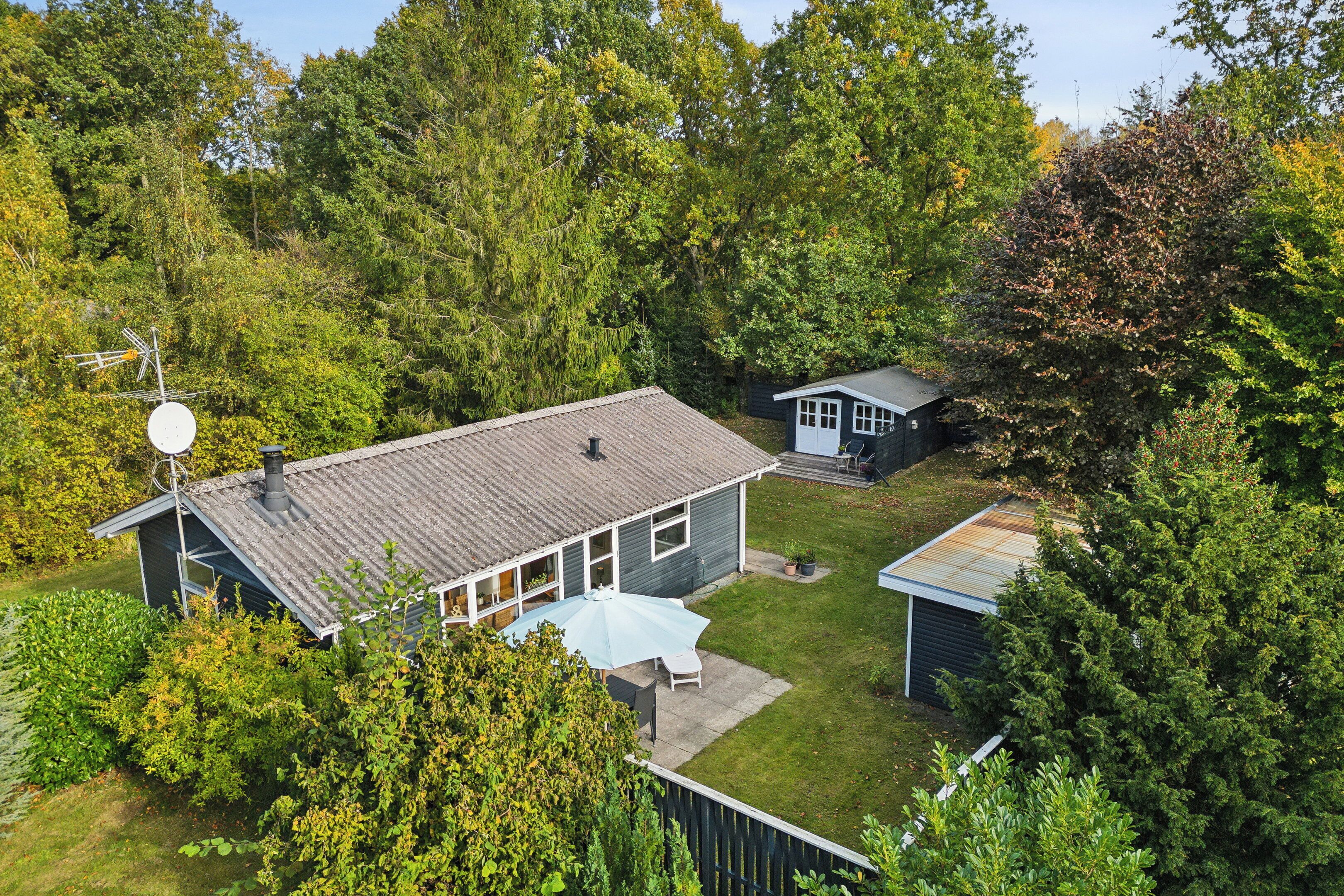 A house with a satellite dish, a covered patio, and a small shed.