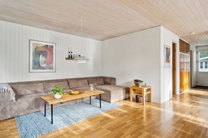 Uma sala de estar moderna com piso de madeira, um sofá marrom, uma mesa de centro e um tapete azul.