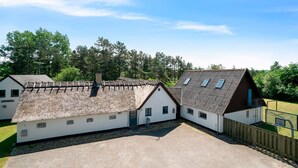 Un bâtiment doté d’un toit de chaume, d’une cour pavée et d’une clôture en bois.