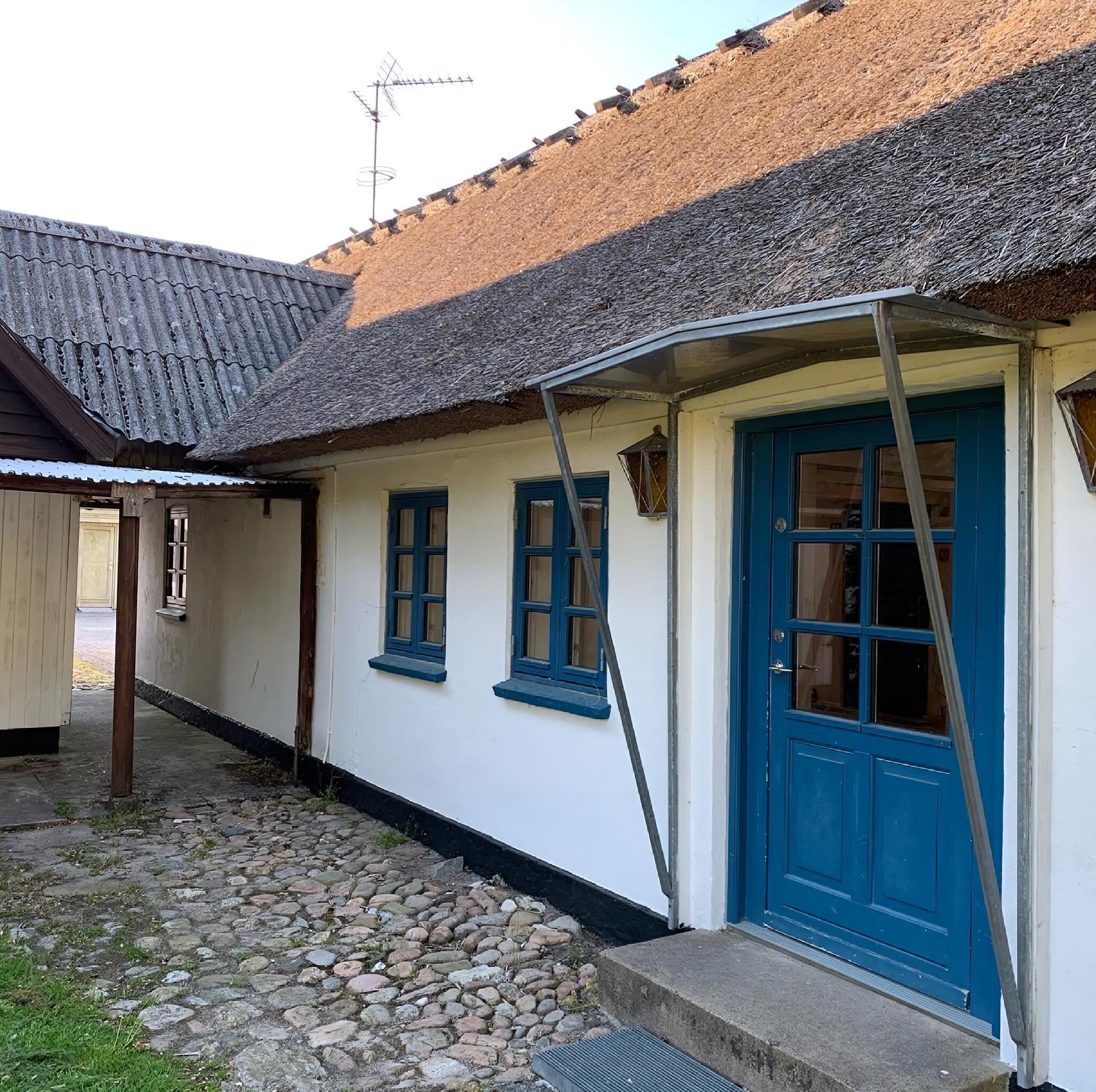A building with a blue door, white walls, and a tiled roof.