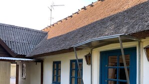 Un bâtiment avec une porte bleue, des murs blancs et un toit recouvert de tuiles.