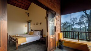 Ein Schlafzimmer mit Bett, Nachttisch und einem Fenster mit Blick auf einen Wald.