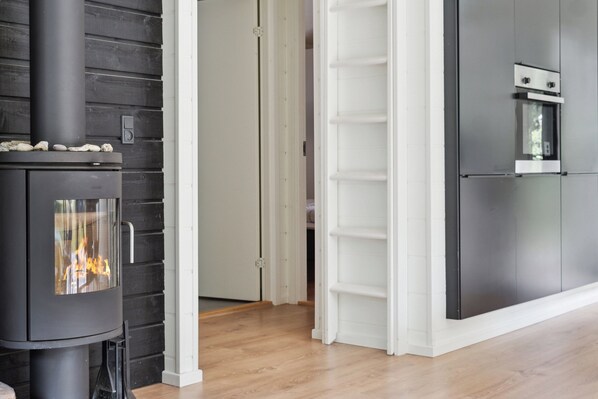 A modern kitchen with a built-in stove, white cabinetry, and a wooden floor. - Scenic summer house in Asserbo (Frederiksværk)