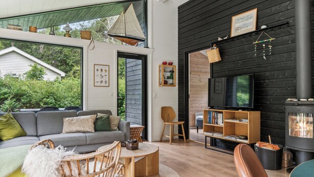 A modern living room with a sofa, chairs, a fireplace, and a television. - Scenic summer house in Asserbo (Frederiksværk)