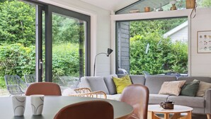 A modern living room with a sofa, chairs, a coffee table, and a dining table. - Scenic summer house in Asserbo (Frederiksværk)