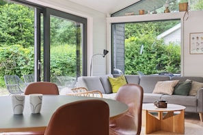 A modern living room with a sofa, chairs, a coffee table, and a dining table.