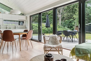 A modern kitchen with white cabinets, a dining area with wooden chairs, and a large sliding glass door leading to a deck.