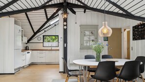 A modern kitchen with white cabinets, a wooden countertop, and a dining area with a round table and black chairs.