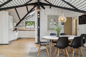 A modern kitchen with white cabinets, a wooden countertop, and a dining area with a white table and black chairs.