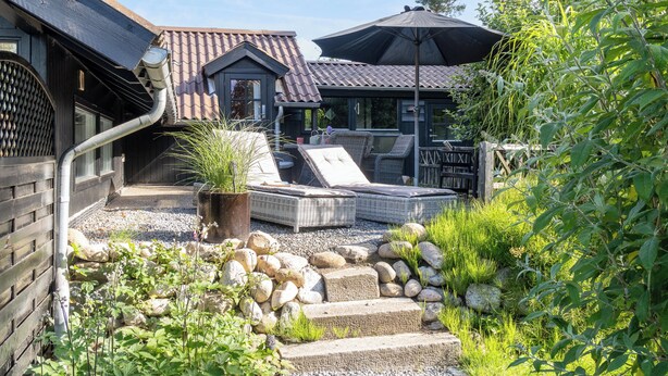 A house with a patio area, outdoor furniture, and a garden with rocks and plants.