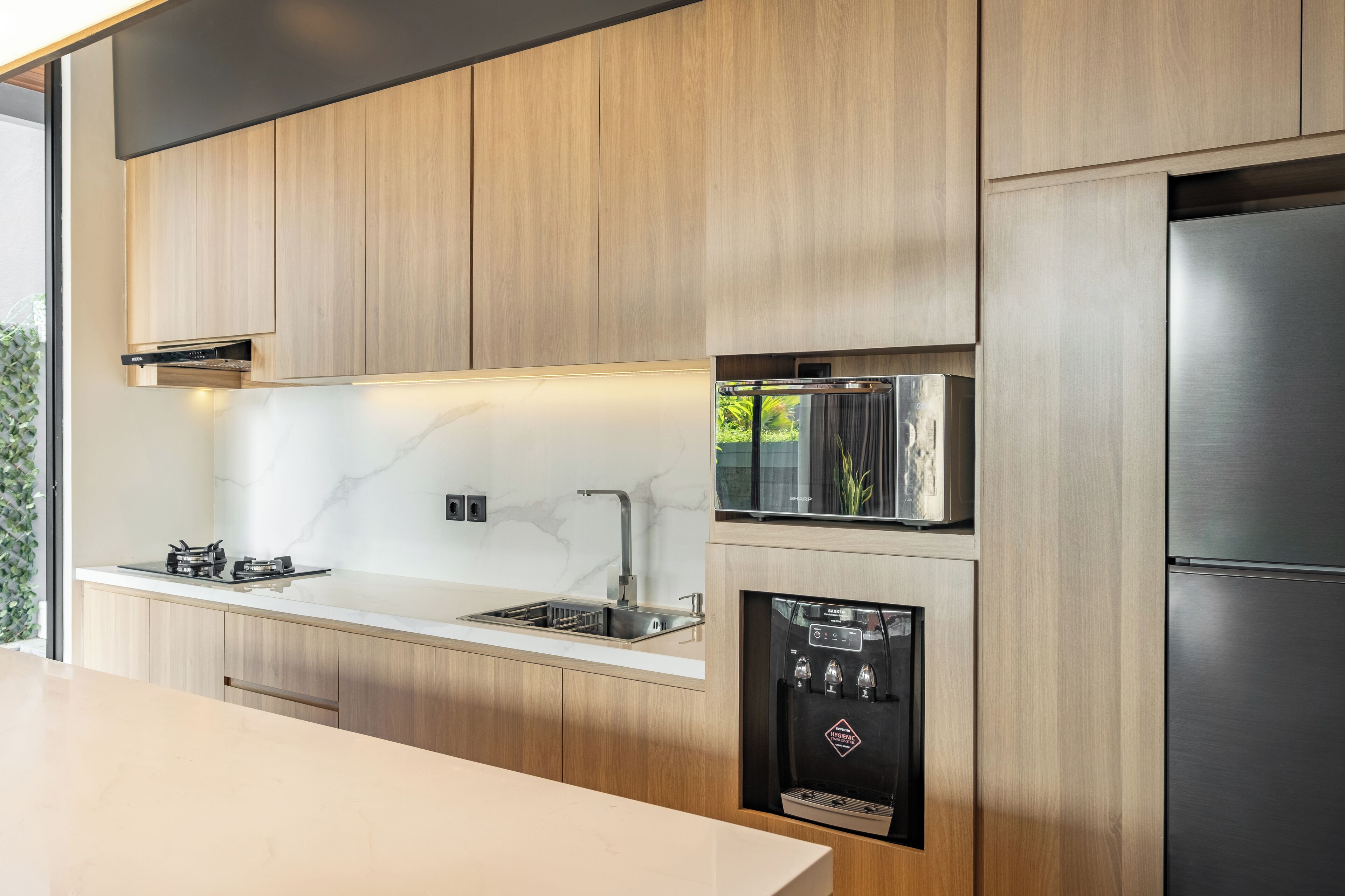 Eine moderne Küche mit Holzausstattung, Edelstahlgeräten und einem integrierten Wasserspender.