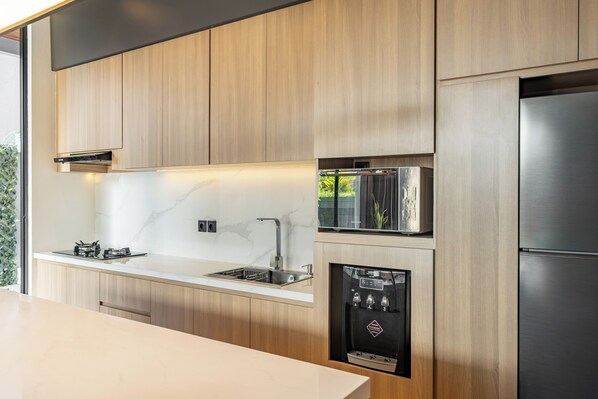 Una cucina moderna con mobili in legno, elettrodomestici in acciaio inossidabile e un dispenser d'acqua integrato.