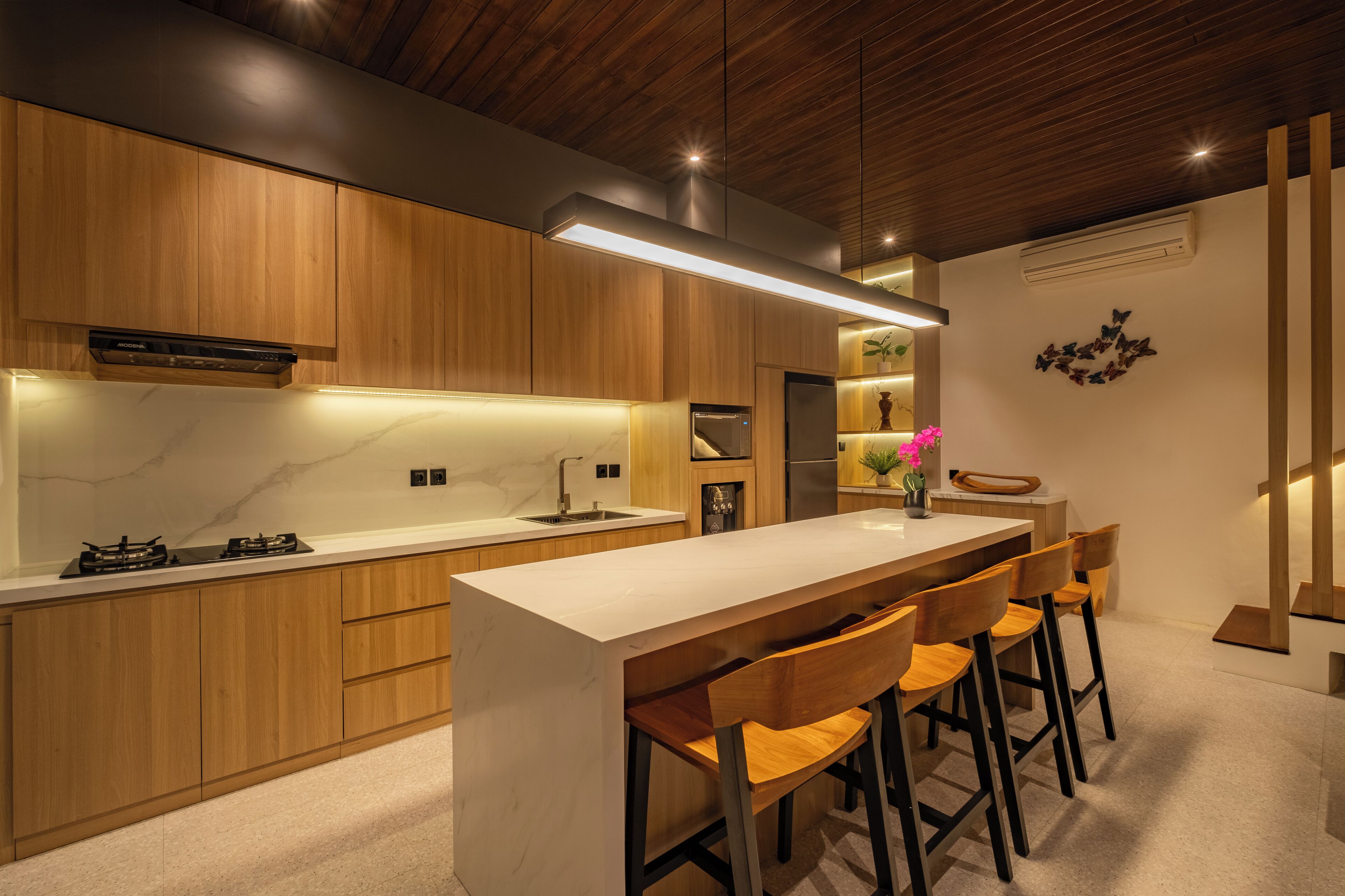Une cuisine moderne avec des meubles en bois, un plan de travail en marbre et un îlot central doté de tabourets de bar.