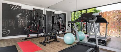 Un gimnasio moderno con equipo cardiovascular, máquinas de pesas y pelotas de ejercicio.