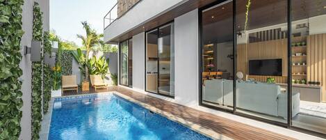 A modern house with a swimming pool, large windows, and a wooden deck.