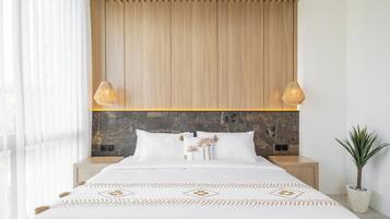 Un dormitorio moderno con techo de listones de madera, cabecera de piedra y cama con colcha estampada.