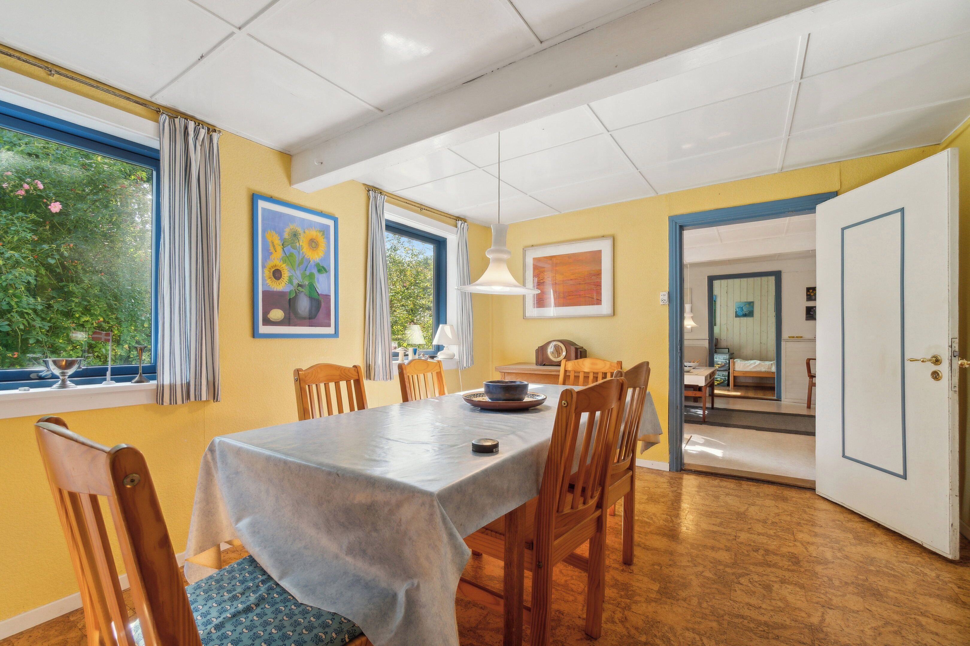 A dining area with a table, chairs, and a view of greenery outside.